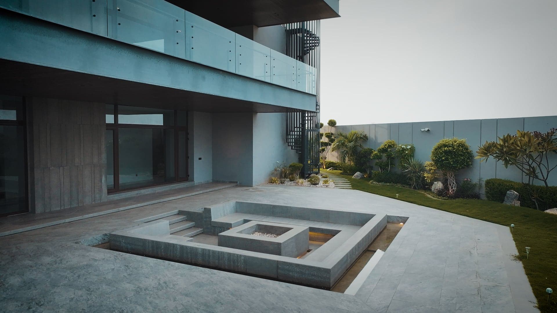 Sunken concrete fire-pit lounge with built-in seating and an open flame at FHU Resorts Karachi