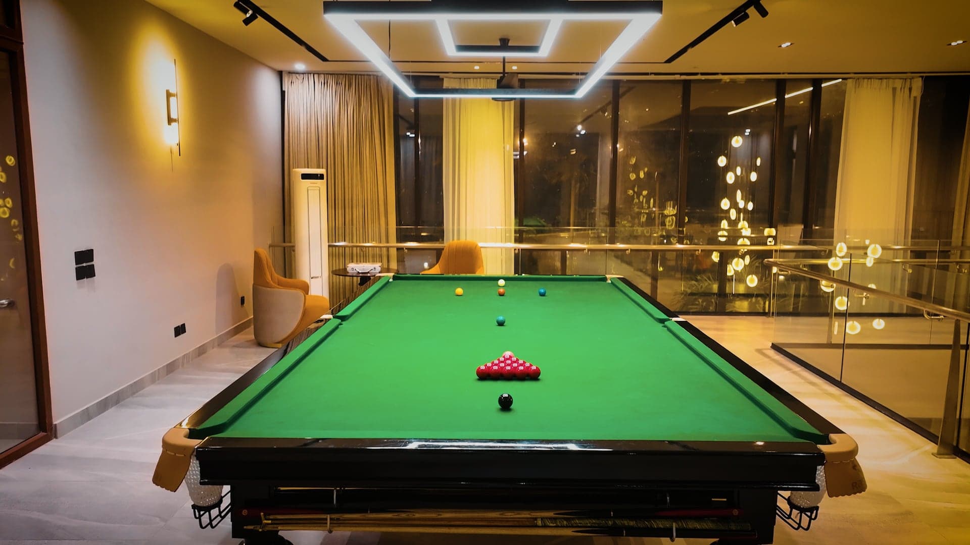 Full-size snooker table set for a frame under a modern light fixture in the billiard room at FHU Resorts Karachi